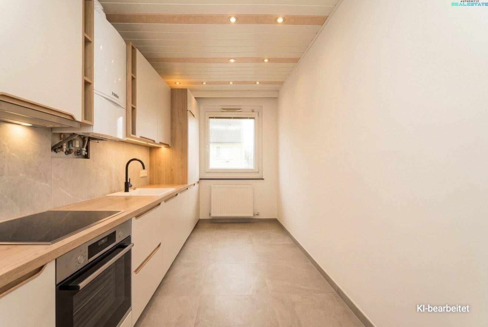 Schmale, moderne Küche mit weißen Schränken, Holzarbeitsplatte und Fenster für Tageslicht.