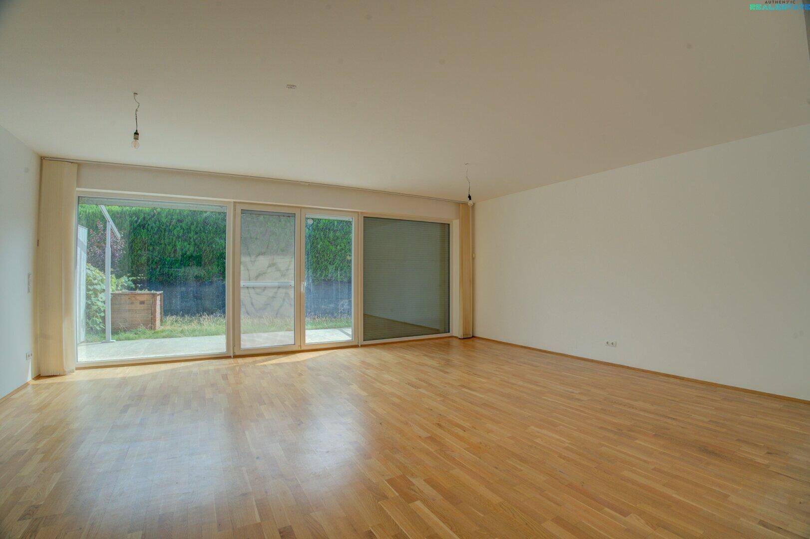 Heller Wohnbereich mit großen Schiebetüren, die Zugang zur Terrasse und zum Garten bieten.