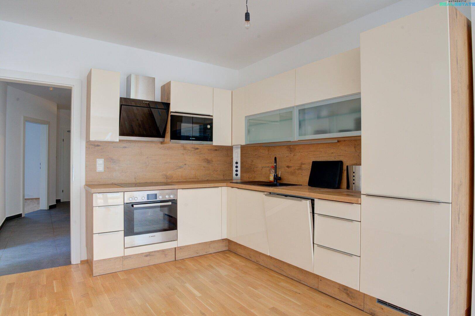 Moderne Einbauküche mit hellen Fronten, Holzdetails und integrierten Elektrogeräten.