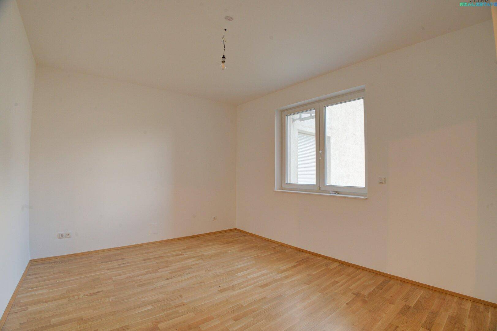 Helles Zimmer mit Parkettboden und Fenster, ideal als Schlaf- oder Arbeitszimmer.