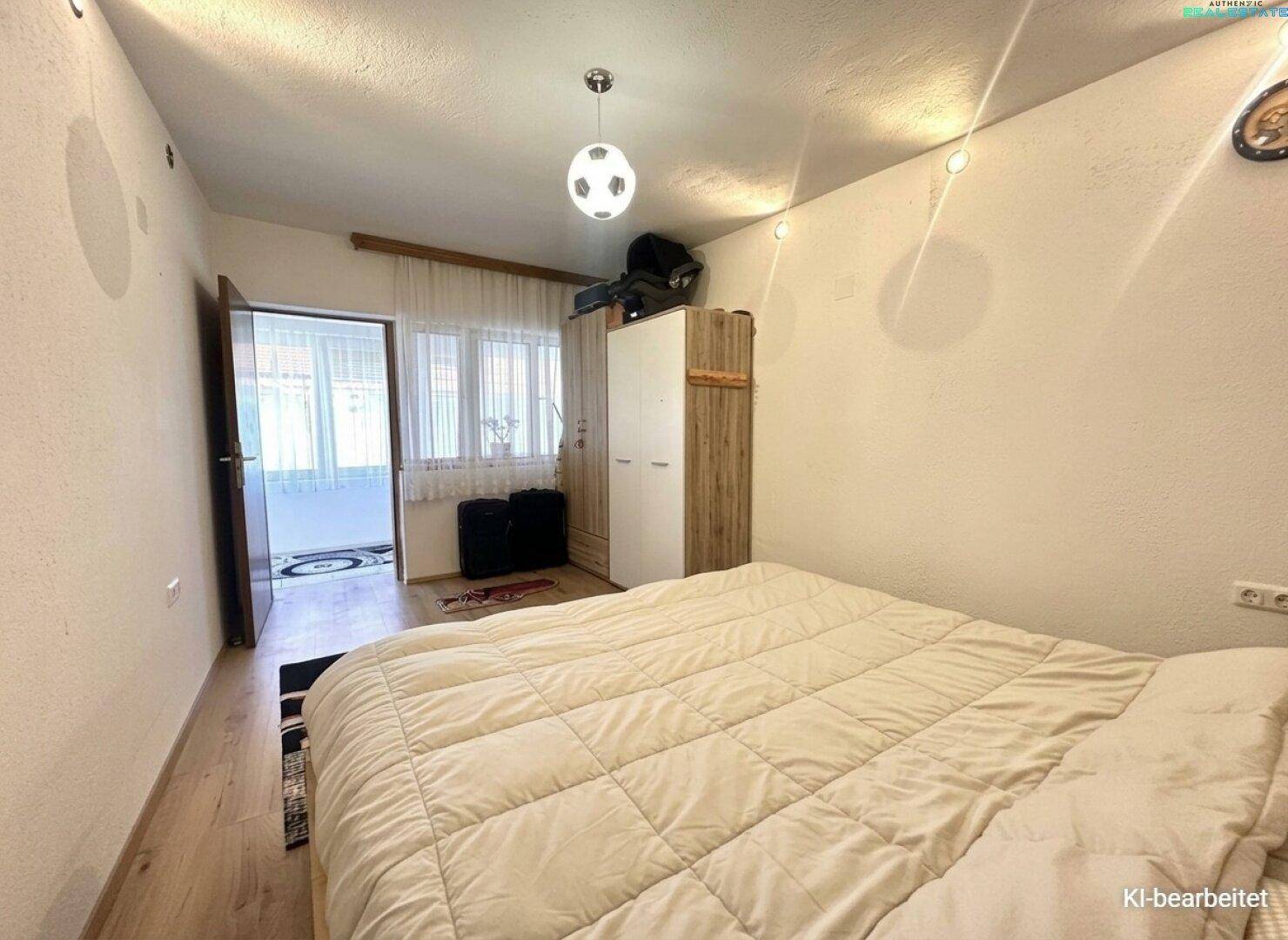 Helles Schlafzimmer mit Holzboden, einem Doppelbett und Zugang zu einem Balkon oder einer Terrasse.