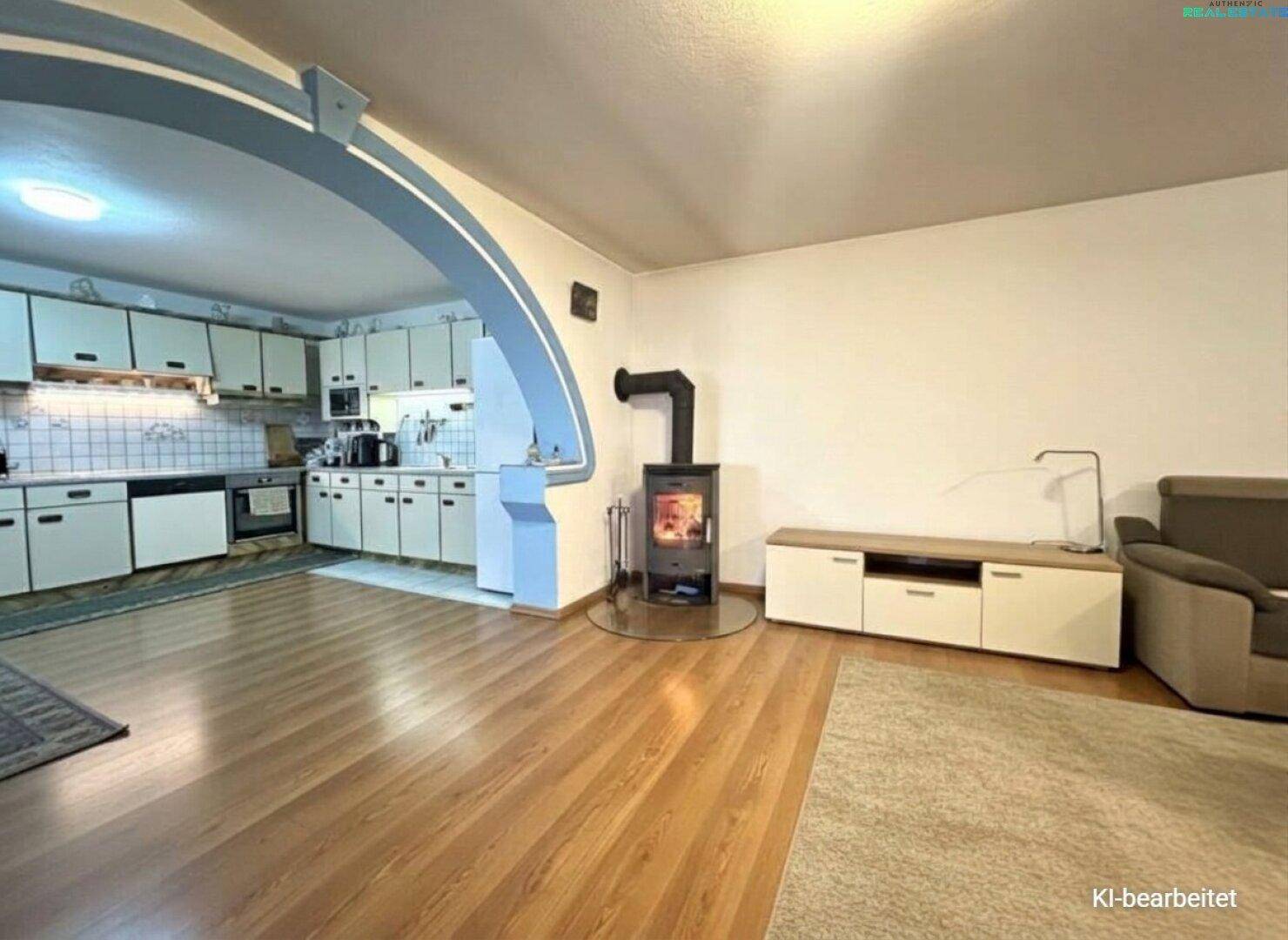 Offener Wohn- und Essbereich mit integrierter Küche, Holzboden und einem Holzofen.