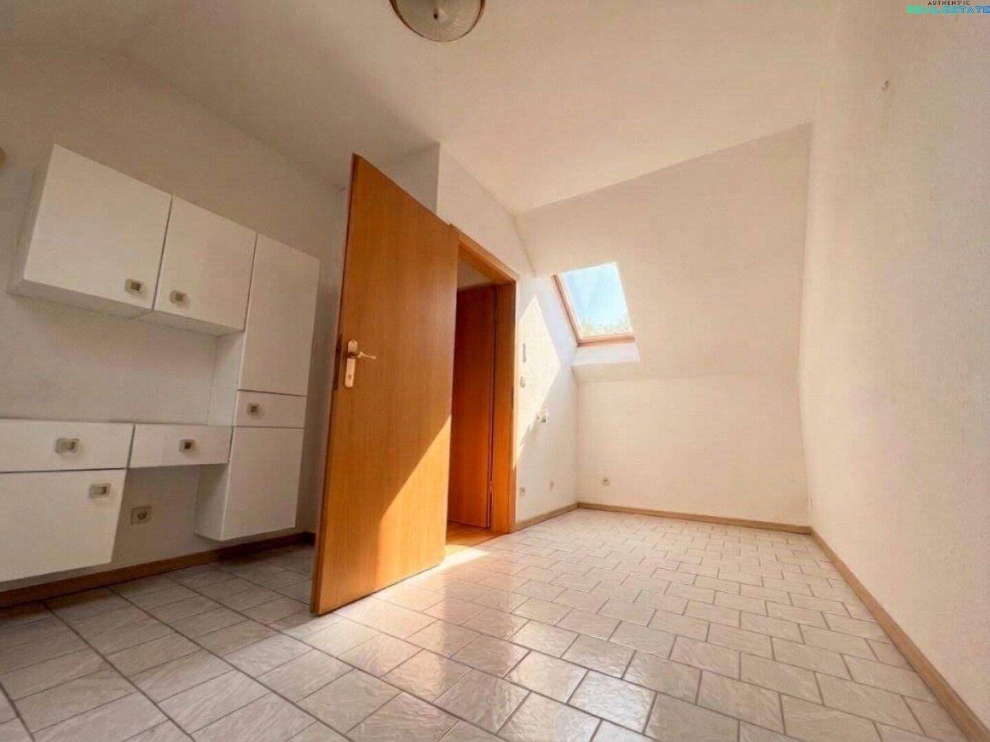 Kleines Zimmer im Dachgeschoss mit Fliesenboden, Dachfenster und Einbauschränken.