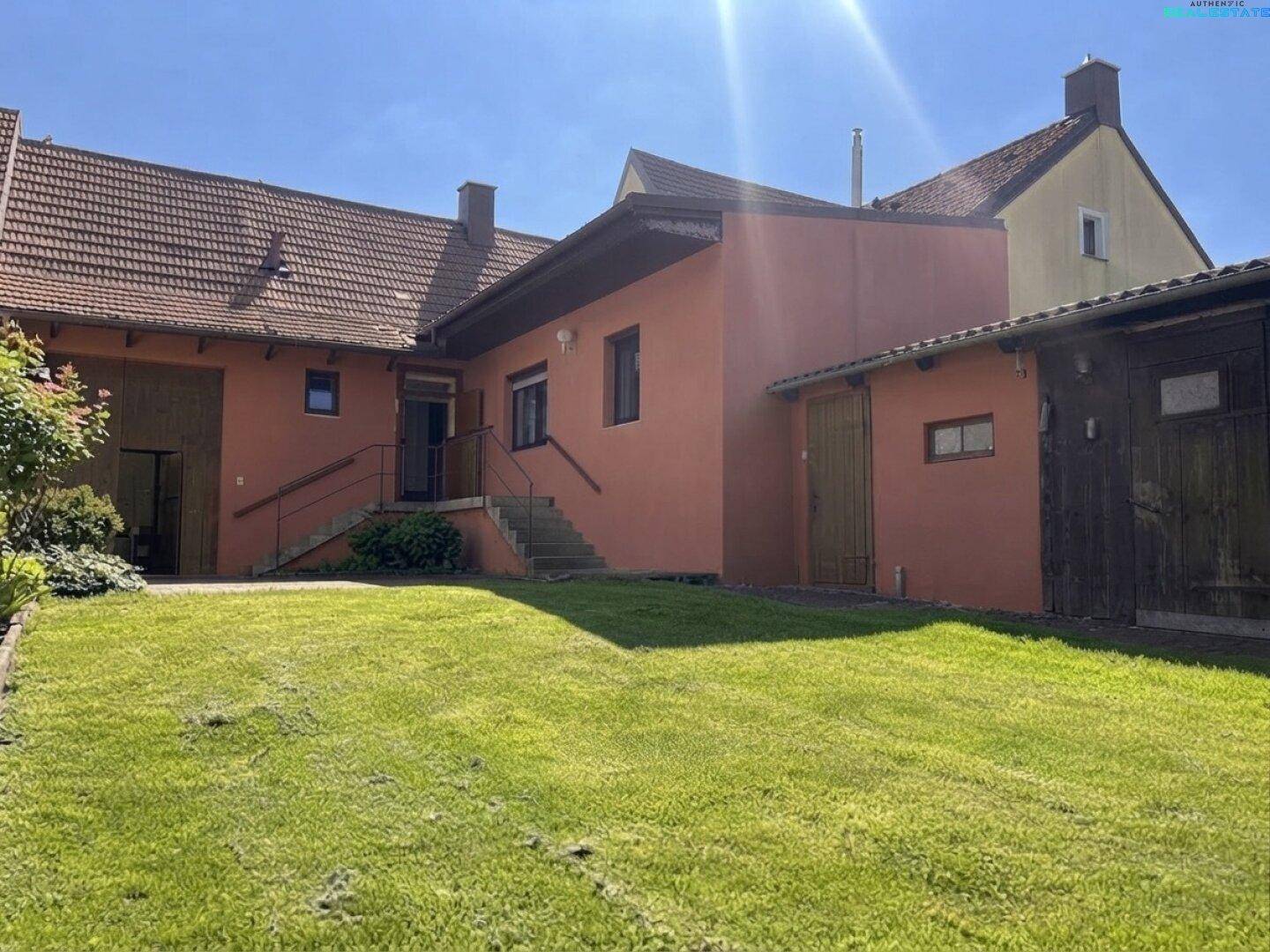 Hinteransicht des Hauses mit großem, gepflegtem Rasen und Außentreppe zum Eingang.