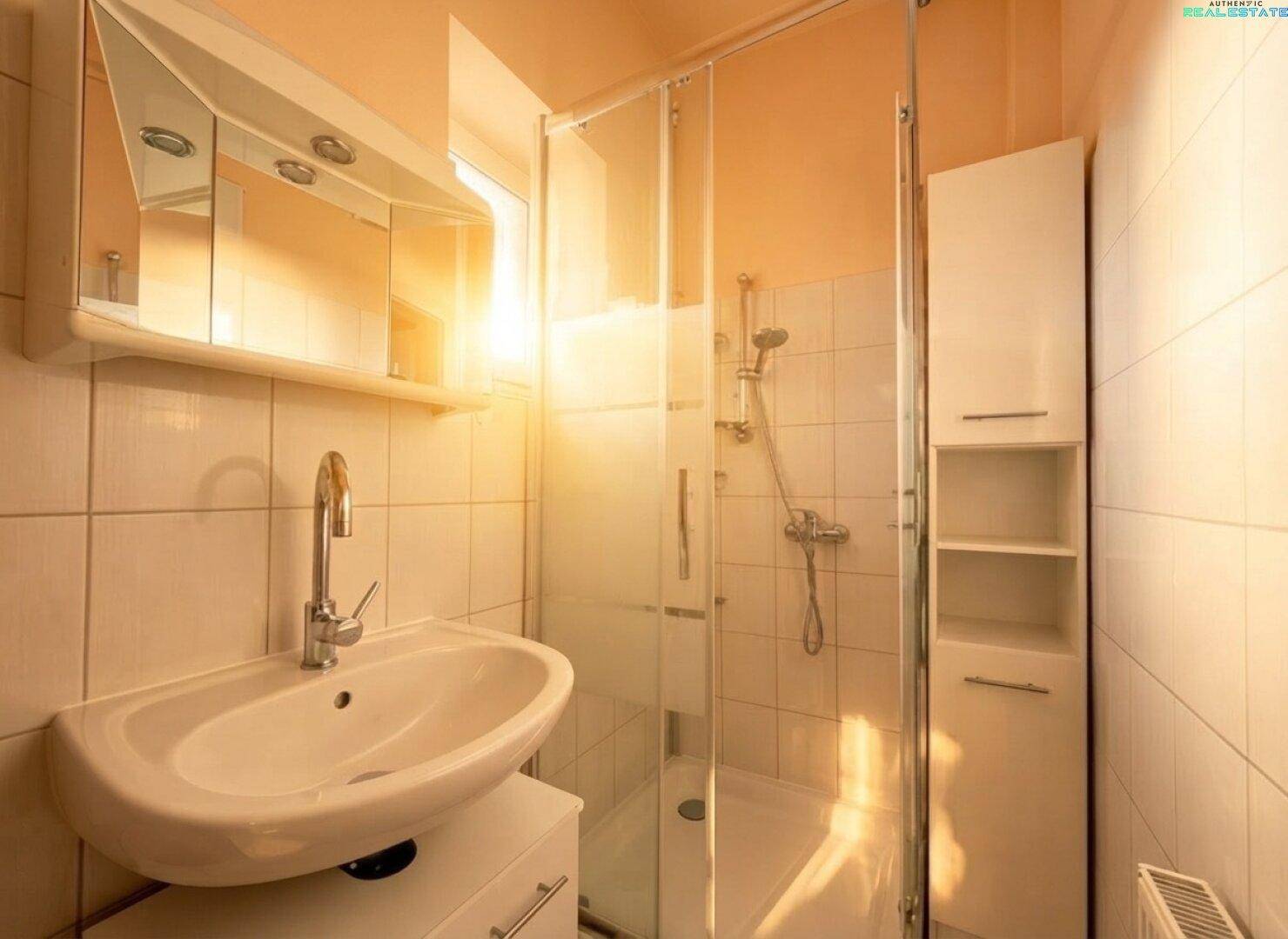 Helles Badezimmer mit Duschkabine, Waschbecken, Spiegelschrank und weißen Fliesen.