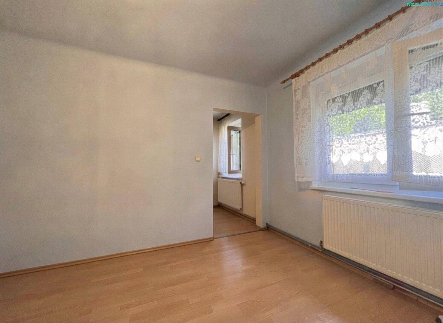 Heller Raum mit zwei Fenstern, hellem Laminatboden und weißen Wänden, ideal für Wohnzwecke.