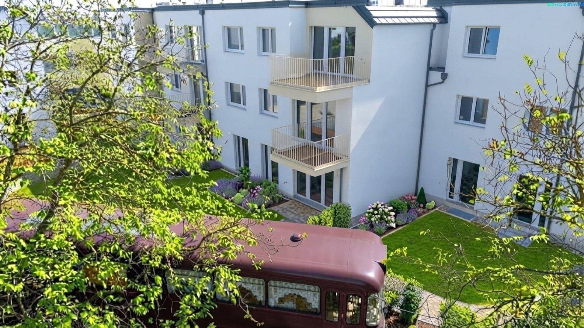 Ansicht der modernen Wohnanlage mit Balkonen und einem grünen Gartenbereich.