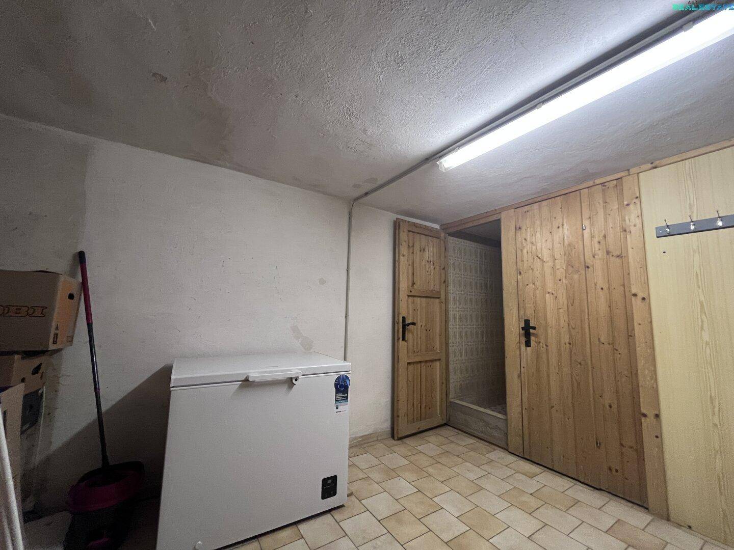 Kellerraum mit gefliestem Boden, Gefriertruhe und Holztüren zu weiteren Abstellbereichen.