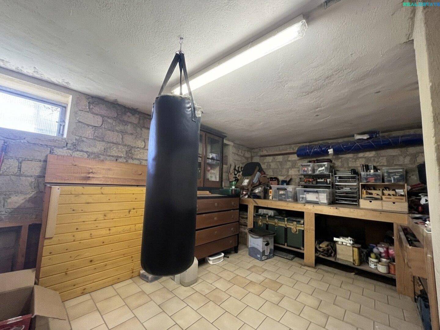 Kellerraum als Werkstatt und Fitnessbereich genutzt, mit Boxsack, Werkbank und Fliesenboden.