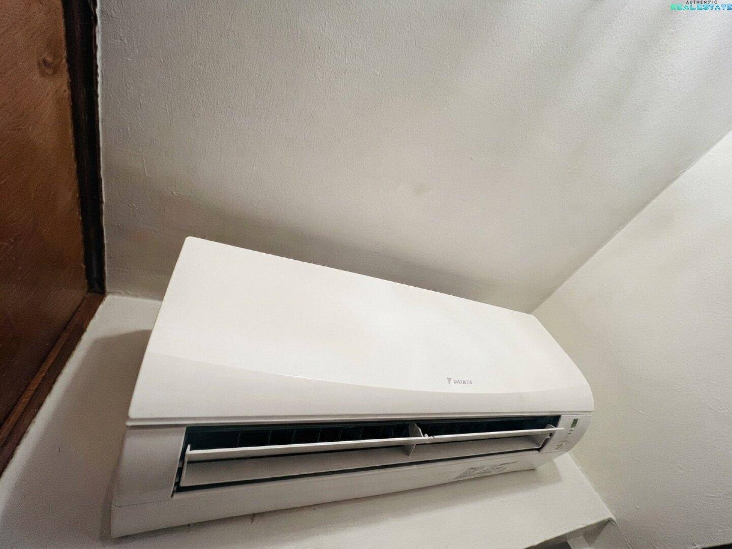 Nahaufnahme einer weißen, an der Wand montierten Klimaanlage für angenehme Raumtemperatur.