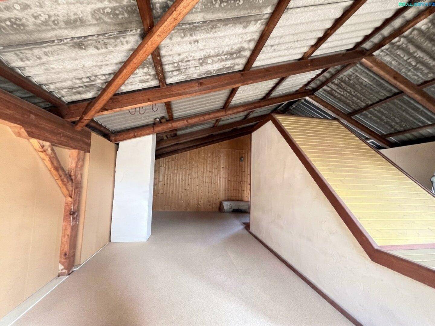 Unausgebauter Dachboden mit sichtbaren Holzbalken und schrägen Wänden.