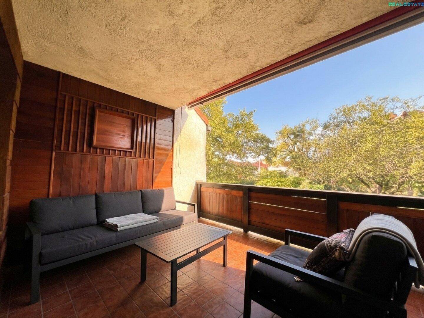 Balkon mit bequemen Gartenmöbeln und Blick ins Grüne.