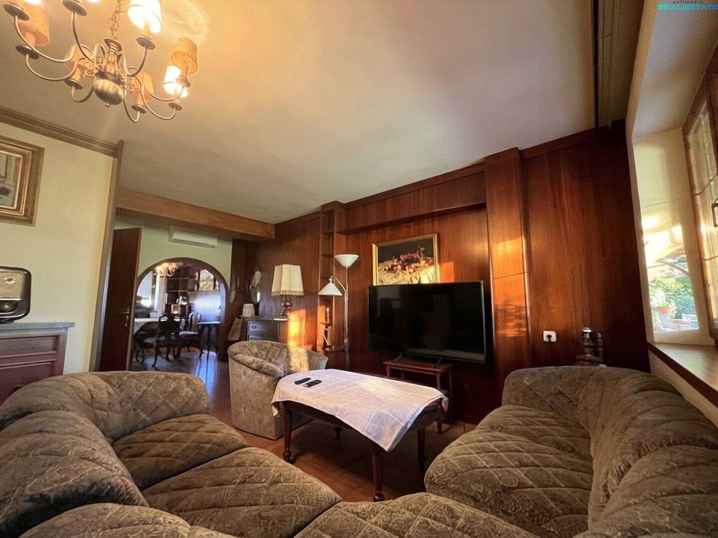 Wohnzimmer mit großer Eckcouch, Couchtisch und Holzvertäfelung.