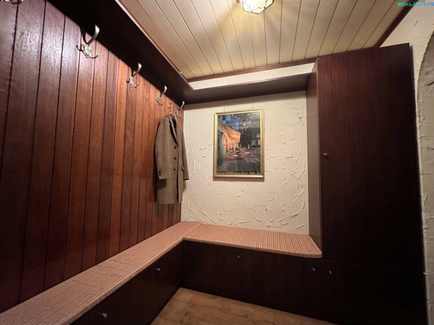 Eingangsbereich mit Holzvertäfelung, Garderobe und integrierter Sitzbank.