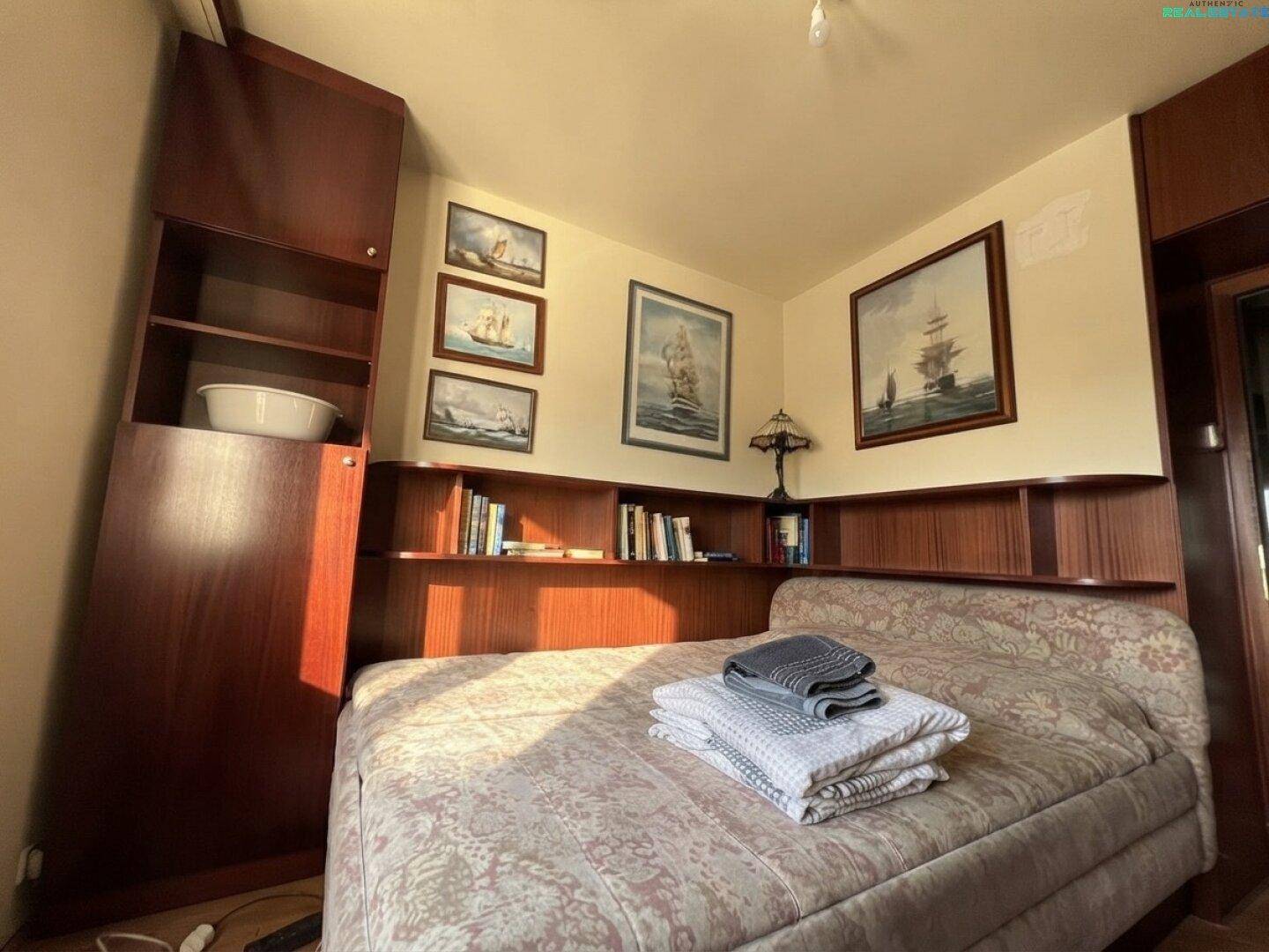 Schlafzimmer mit Einzelbett, eingebauten Holzregalen und maritimen Bildern.