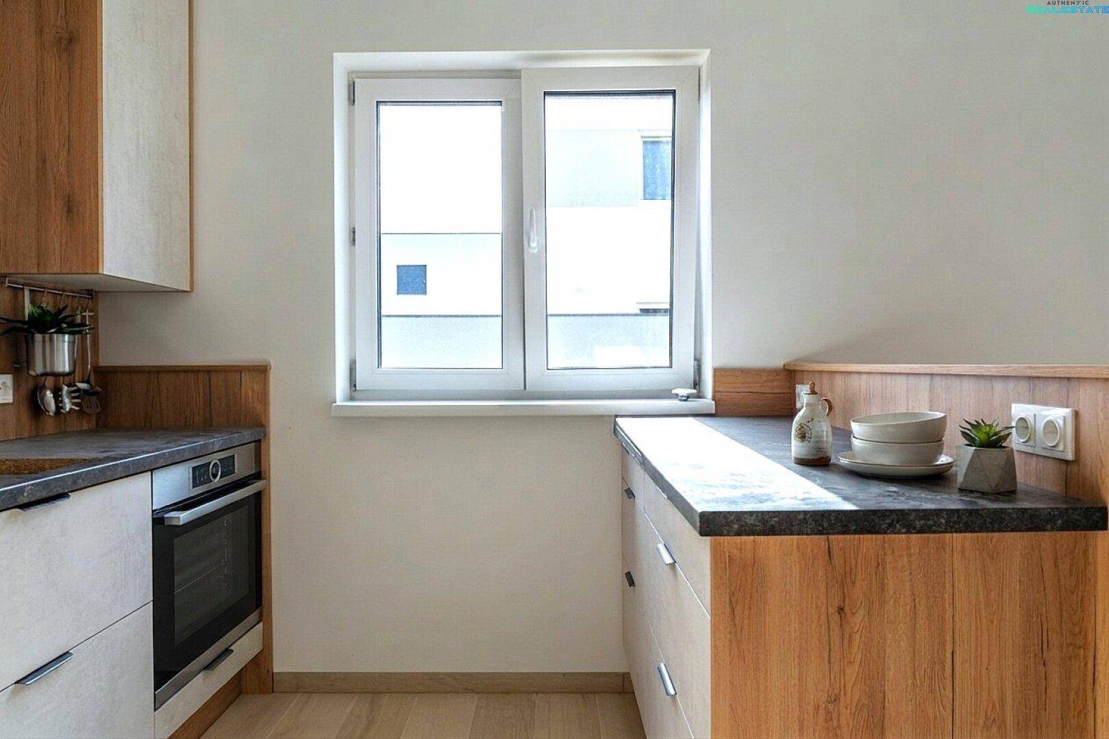 Küchenfenster mit Blick nach draußen und Arbeitsplatte mit Geschirr.