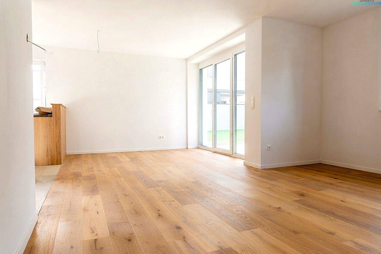 Heller, leerer Raum mit Holzboden und großer Schiebetür zum Außenbereich.