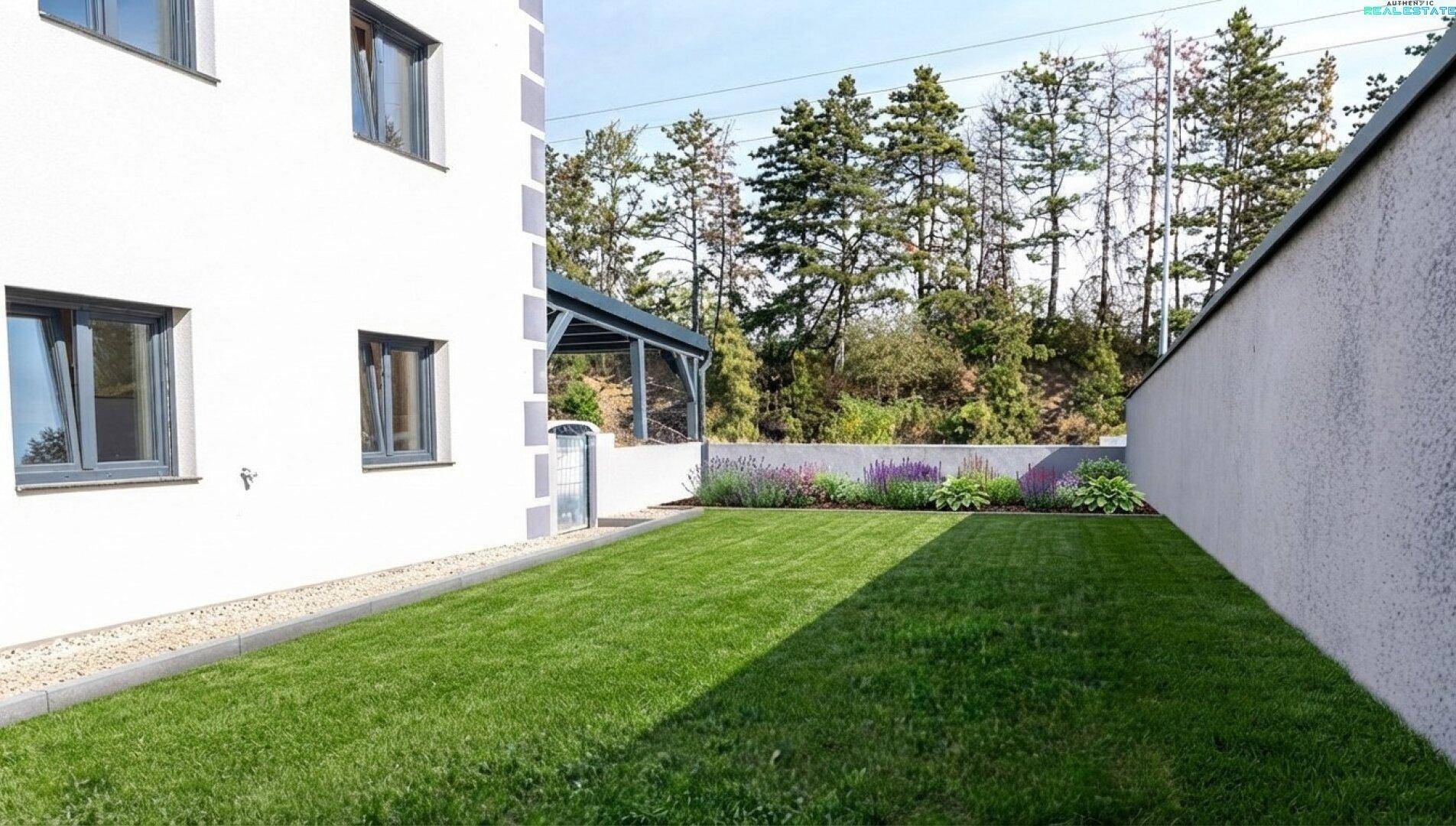 Gepflegter Garten mit Rasenfläche und Blumenbeeten neben dem Haus.
