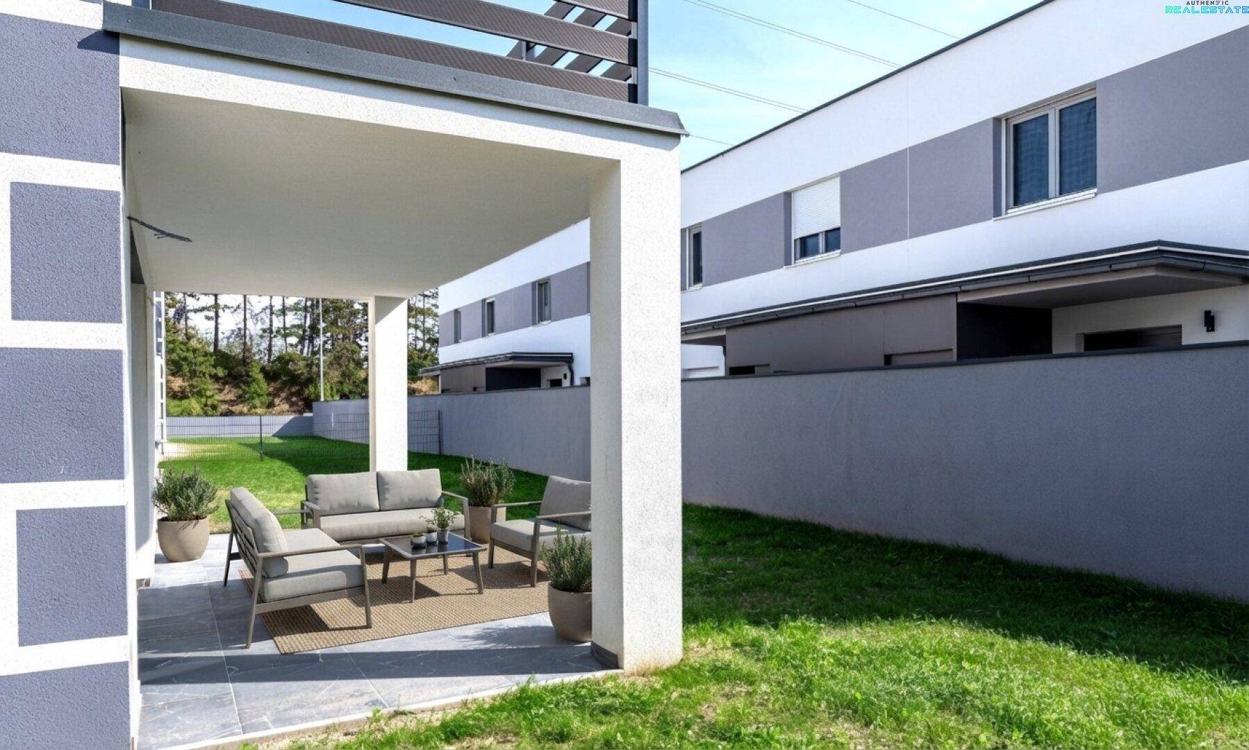 Überdachte Terrasse mit modernen Gartenmöbeln und Blick ins Grüne.
