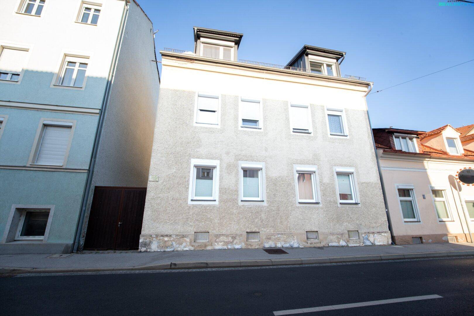 Vorderansicht eines Mehrfamilienhauses an der Straße mit mehreren Fenstern und klassischer Fassade.