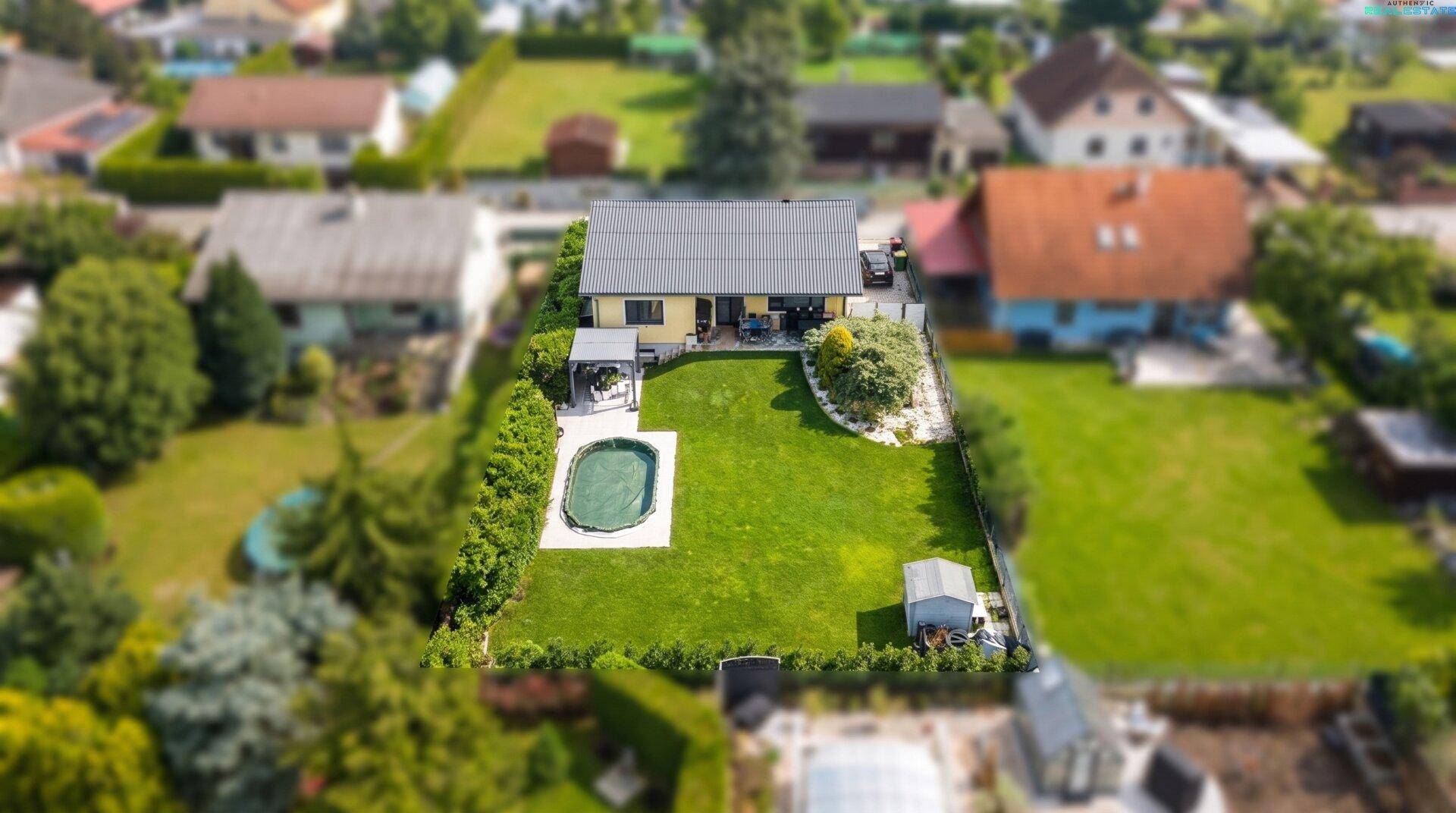Luftaufnahme des hinteren Gartens mit großzügiger Rasenfläche, Pool und Gartenhaus.