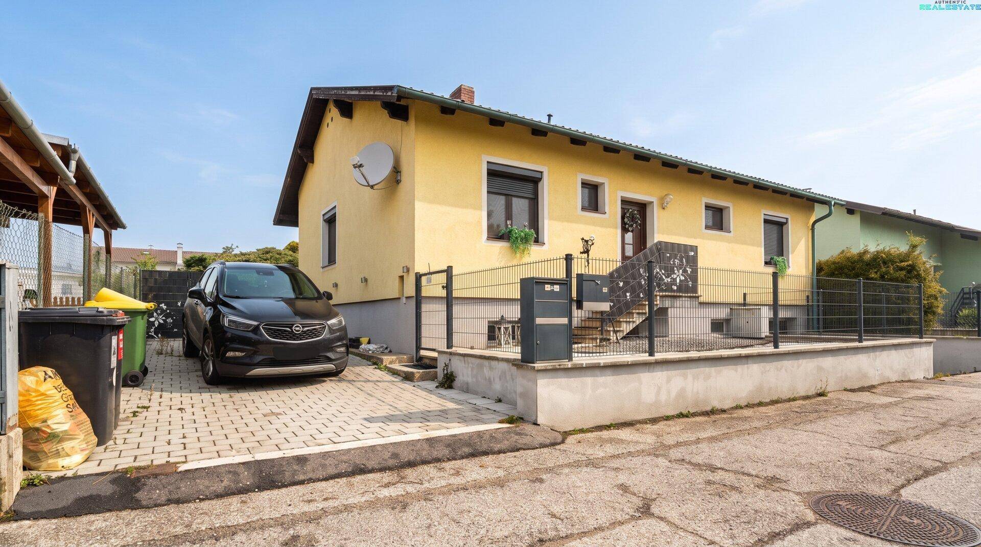 Seitenansicht des Hauses mit gepflasterter Einfahrt und Stellplatz für ein Fahrzeug.