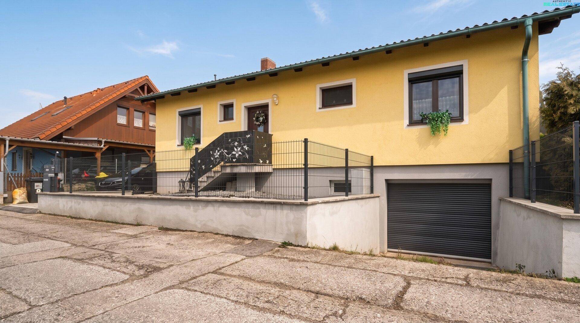 Vorderansicht des Hauses mit integrierter Garage und gepflegtem Vorgartenbereich.