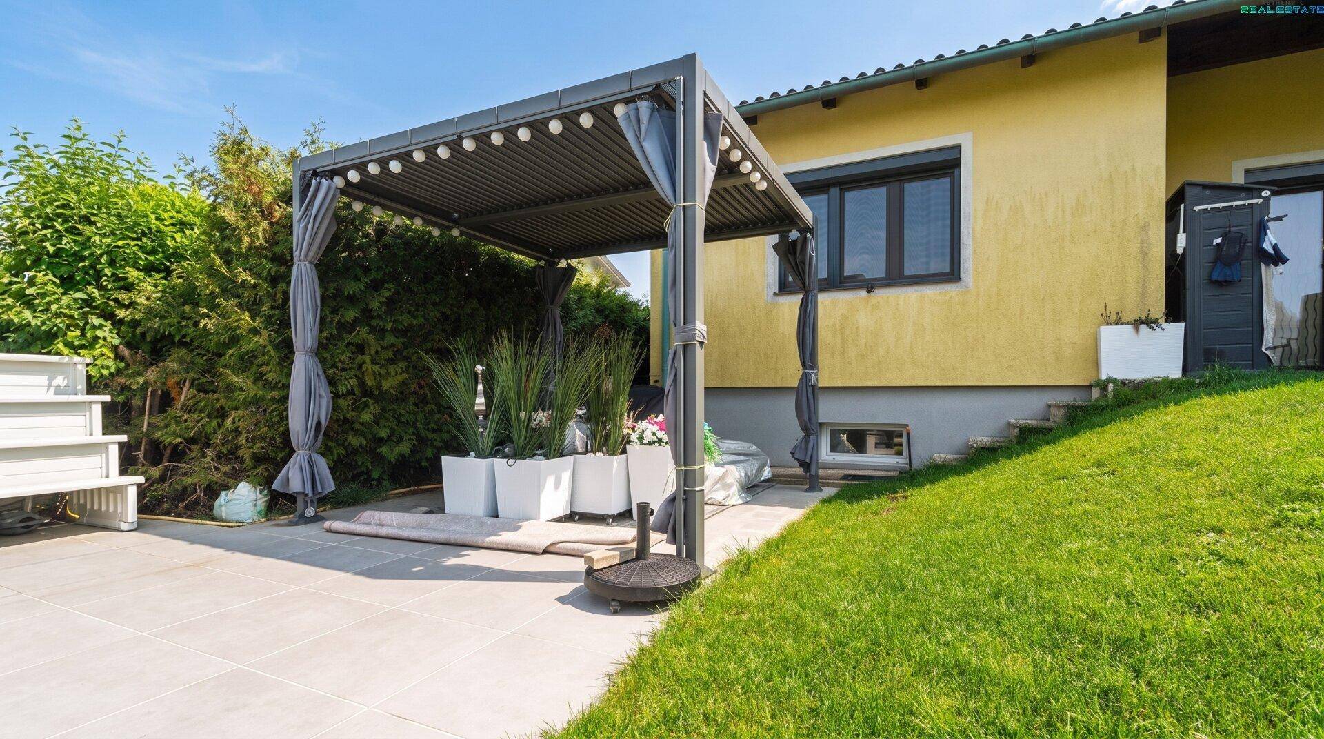 Gemütliche Terrasse mit Pergola, Sitzgelegenheiten und Blick auf den Garten.