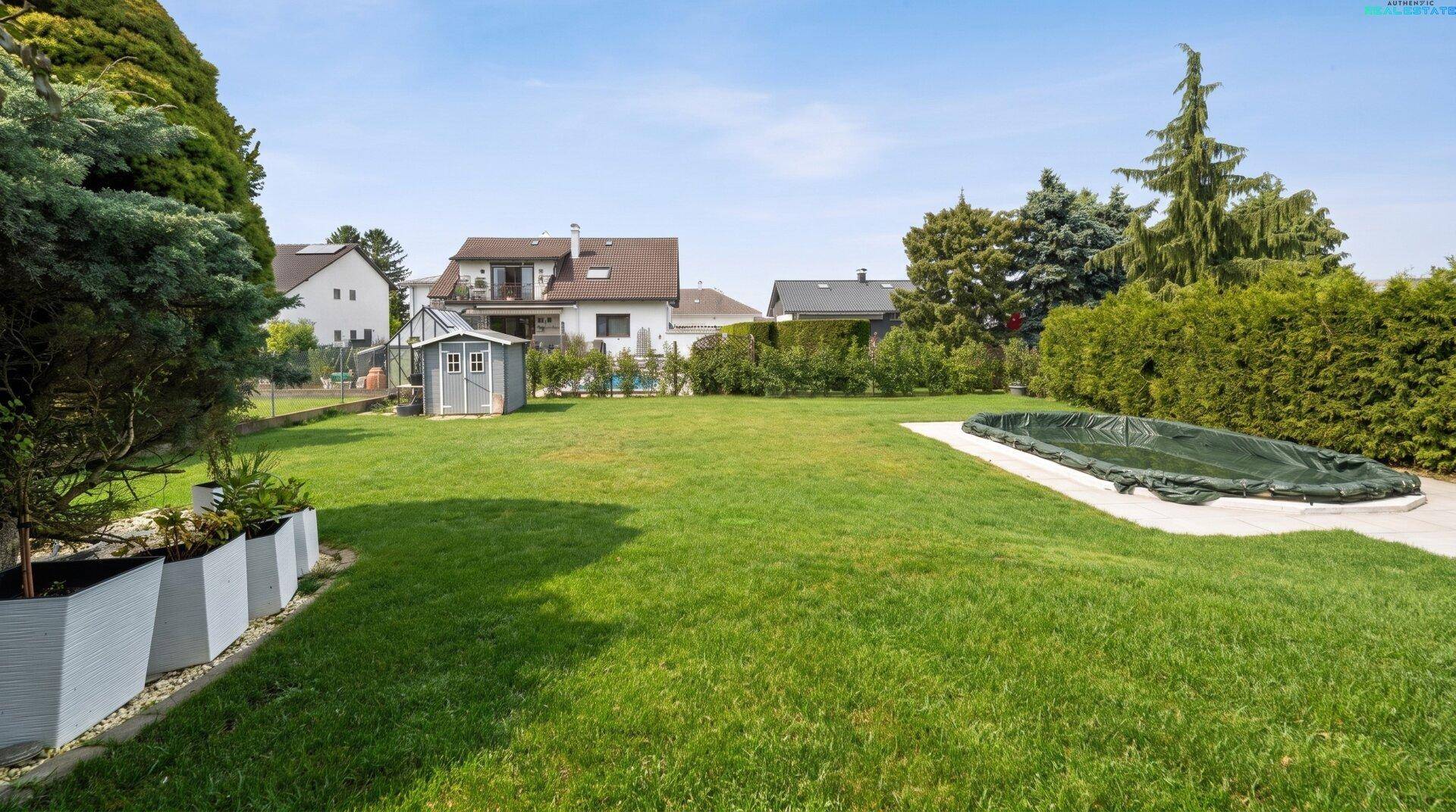 Großer, sonniger Garten mit Rasenfläche, Gartenhaus und abgedecktem Poolbereich.