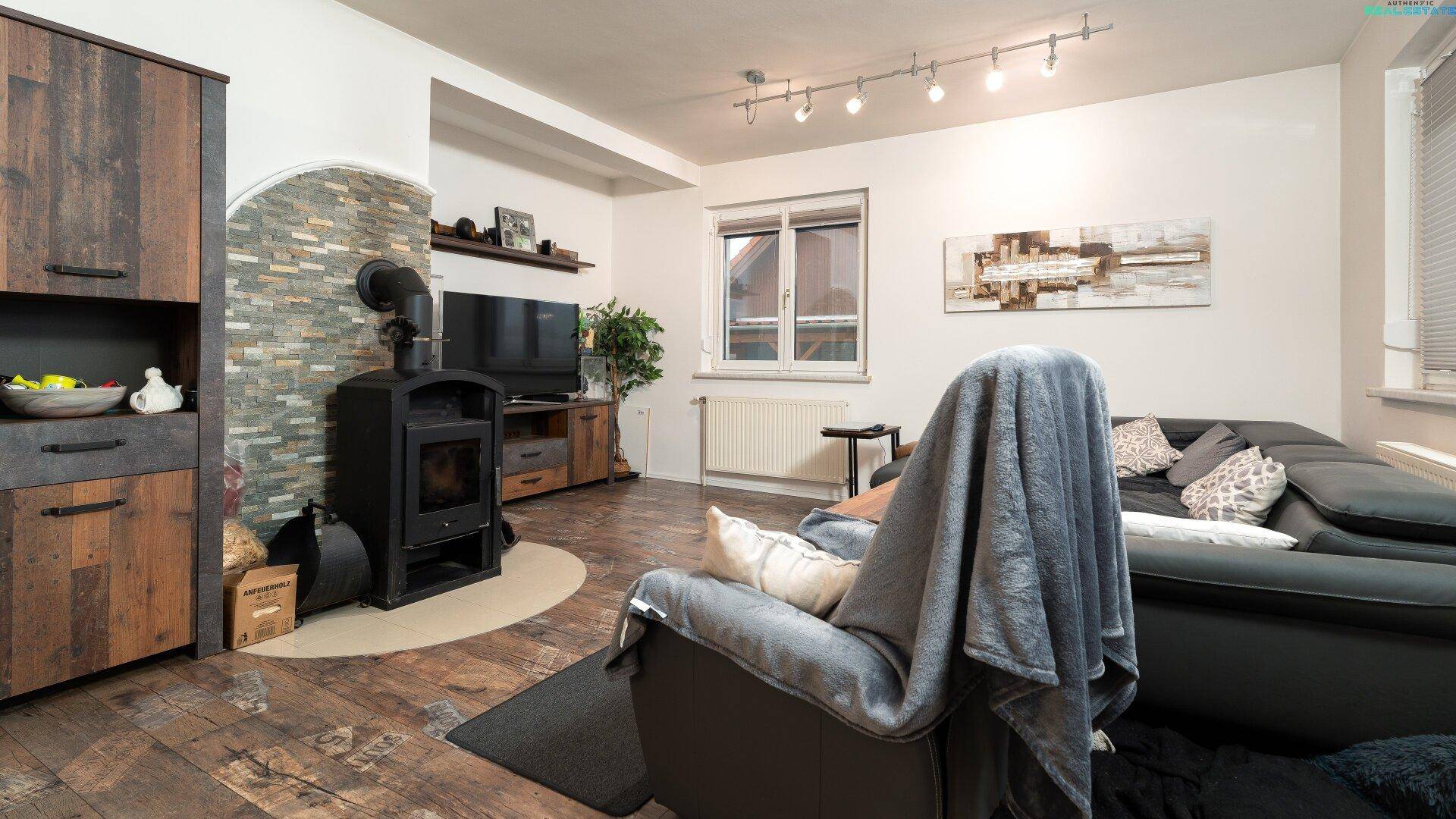 Gemütliches Wohnzimmer mit Holzofen, bequemer Couch und modernem Holzfußboden.