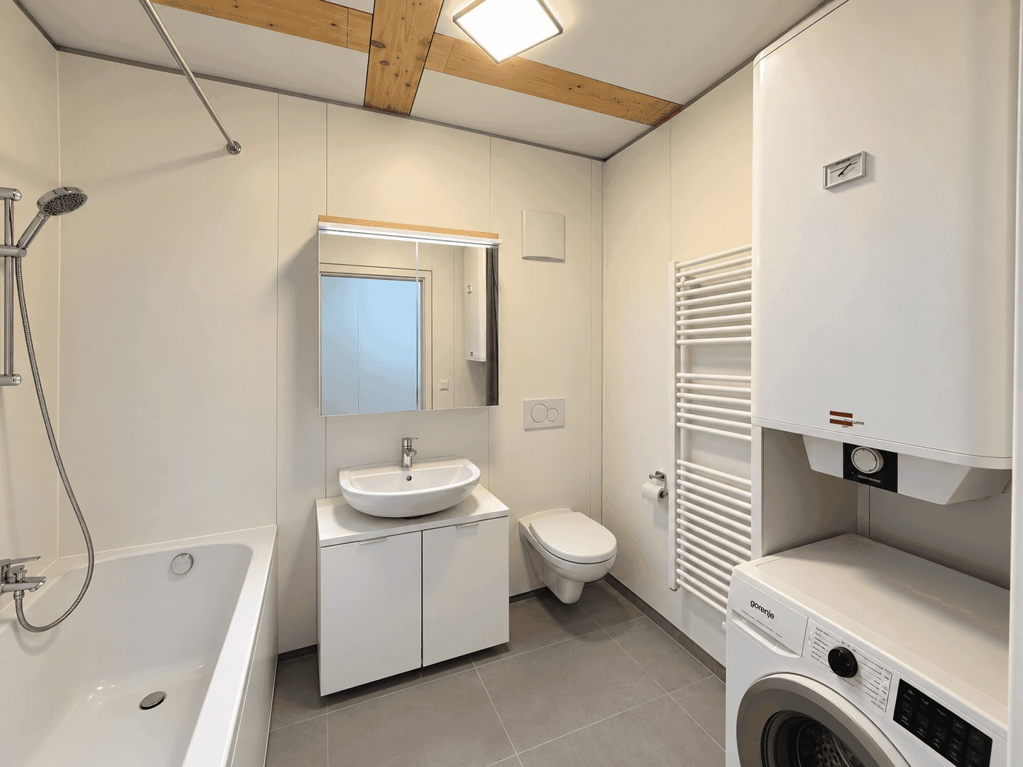 Modernes Badezimmer mit Badewanne, Dusche, Waschmaschine und beheiztem Handtuchhalter.