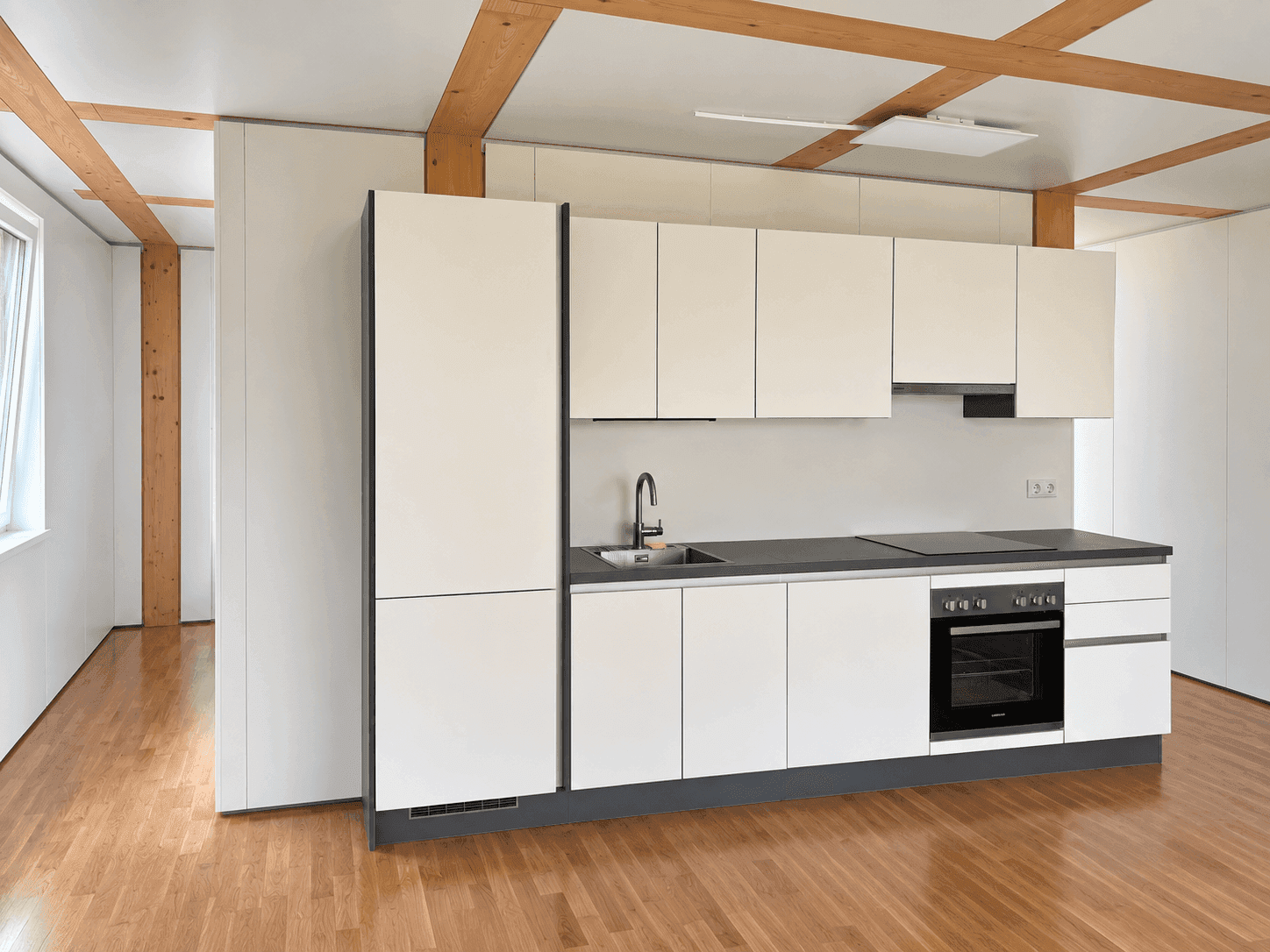 Moderne Einbauküche mit weißen Fronten, dunkler Arbeitsplatte und integrierten Geräten.