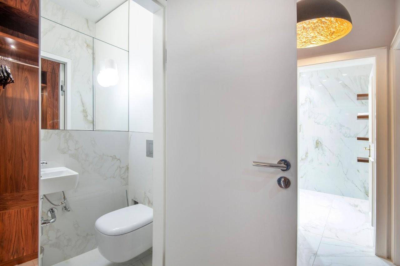Heller Flur mit Zugang zu einem modernen Gäste-WC und einem luxuriösen Badezimmer.
