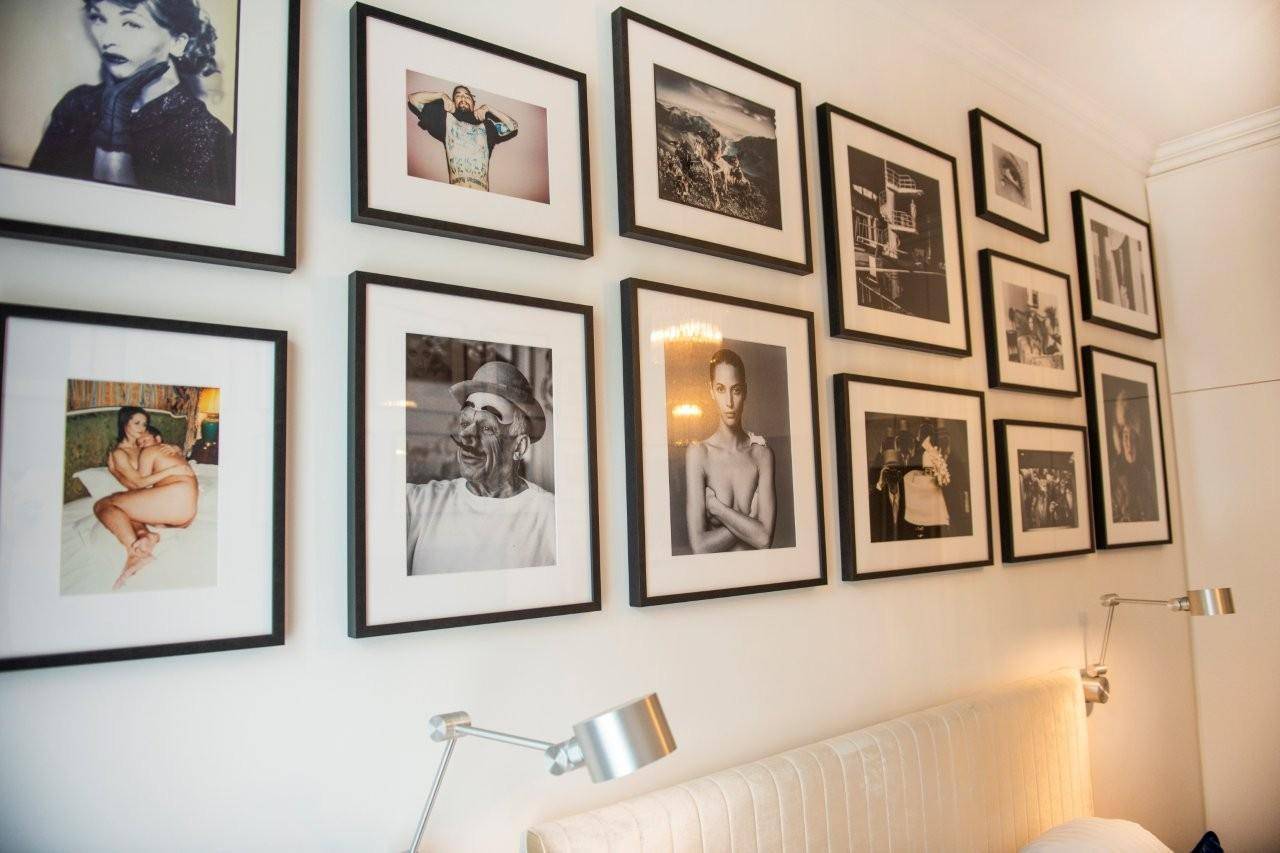 Detailansicht einer Wand im Schlafzimmer mit einer stilvollen Galerie aus gerahmten Schwarz-Weiß-Fotos.