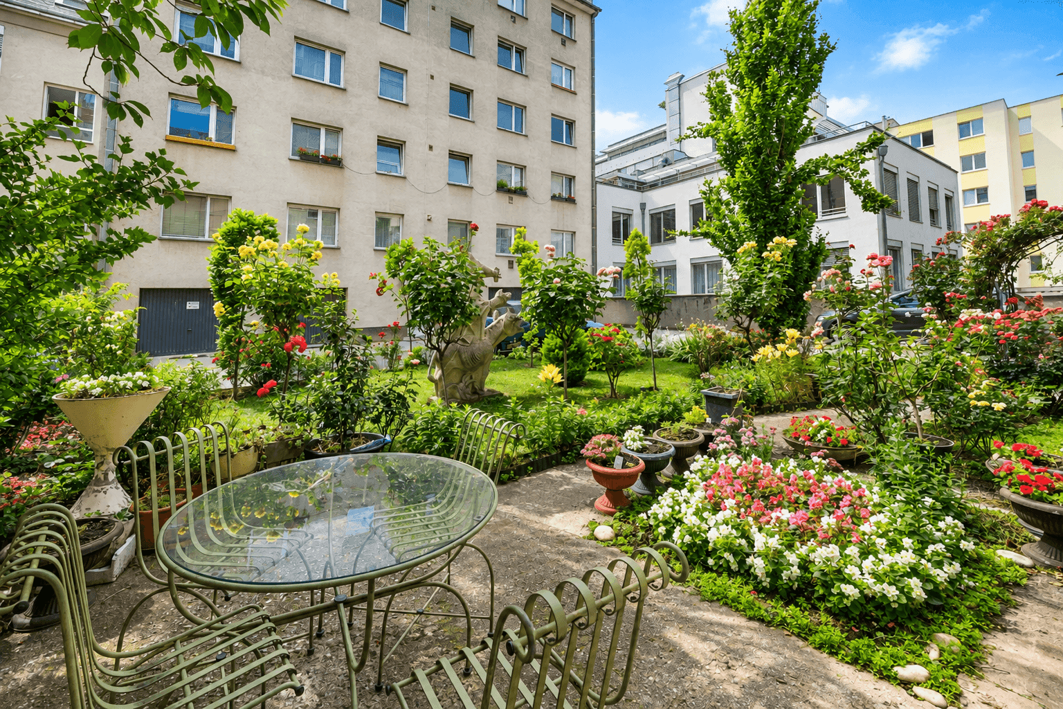 Gepflegter Gemeinschaftsgarten mit Sitzgelegenheiten und vielfältiger Bepflanzung.