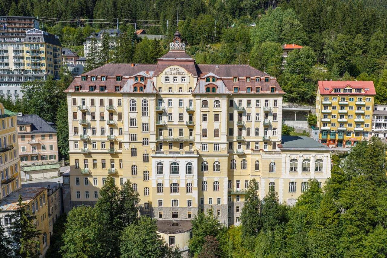 Majestätisches Grand Hotel mit klassischer Architektur, umgeben von üppiger grüner Landschaft.