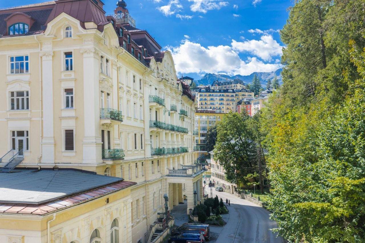 Elegantes historisches Gebäude mit vielen Balkonen und Blick auf die Berge und die Stadt.