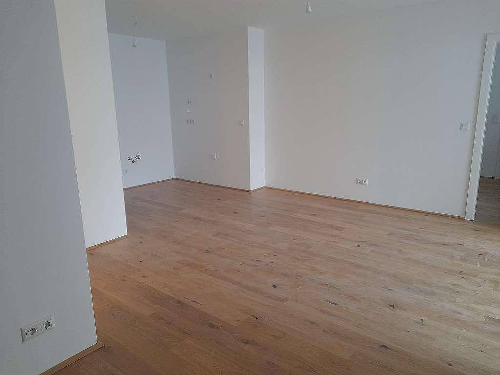 Geräumiger, heller Innenraum mit hochwertigem Holzfußboden und frisch gestrichenen weißen Wänden.