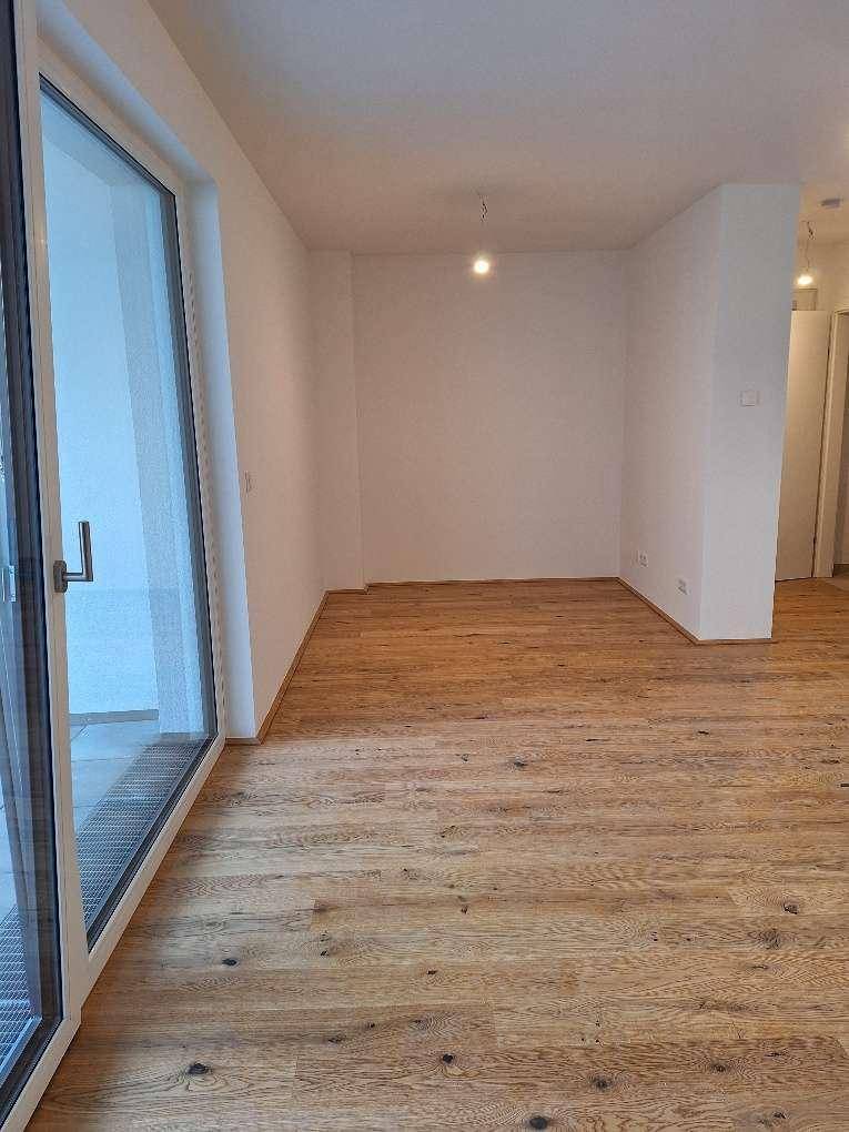 Lichtdurchfluteter Wohnbereich mit Holzfußboden und großer Glasfront zum Außenbereich.