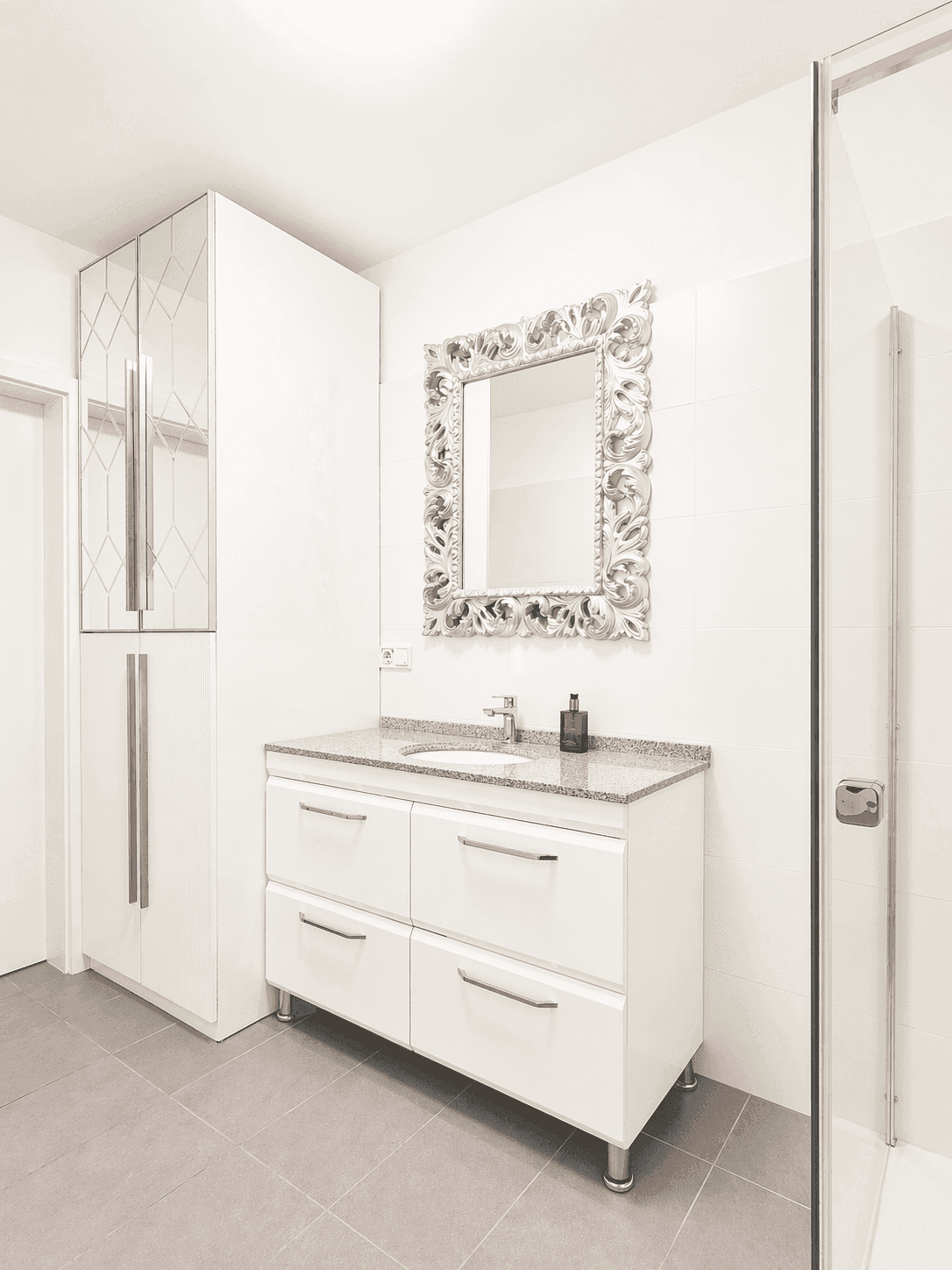 Modernes Badezimmer mit Einzelwaschbecken, großer Dusche und dekorativem Spiegel.