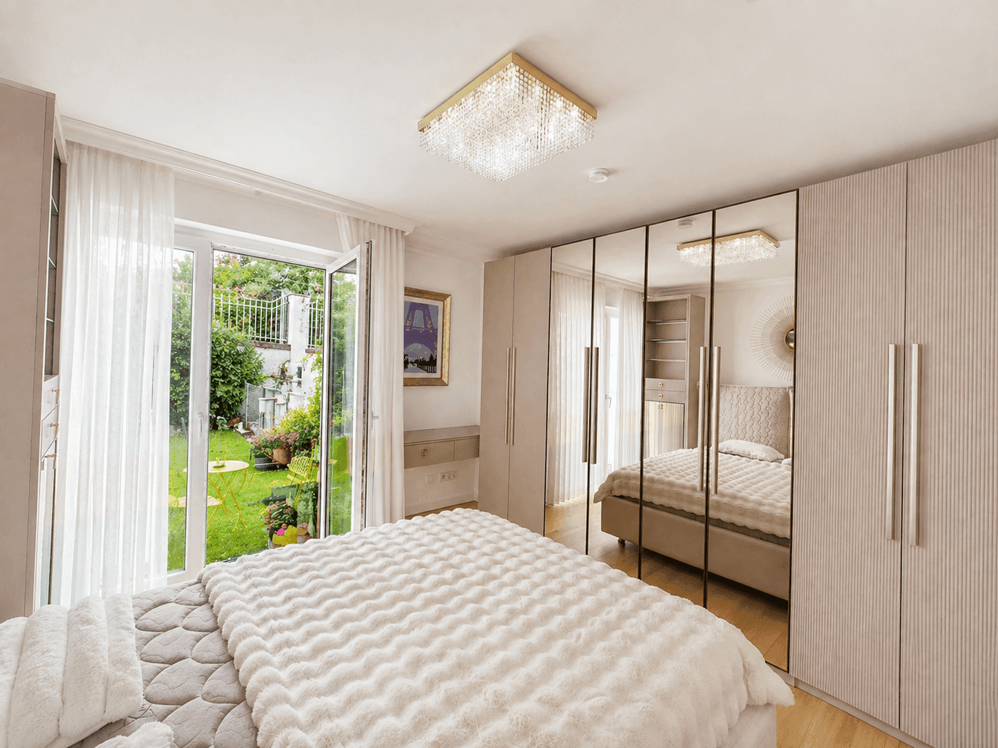 Helles Schlafzimmer mit direktem Zugang zum grünen Garten und eleganten Spiegelschränken.