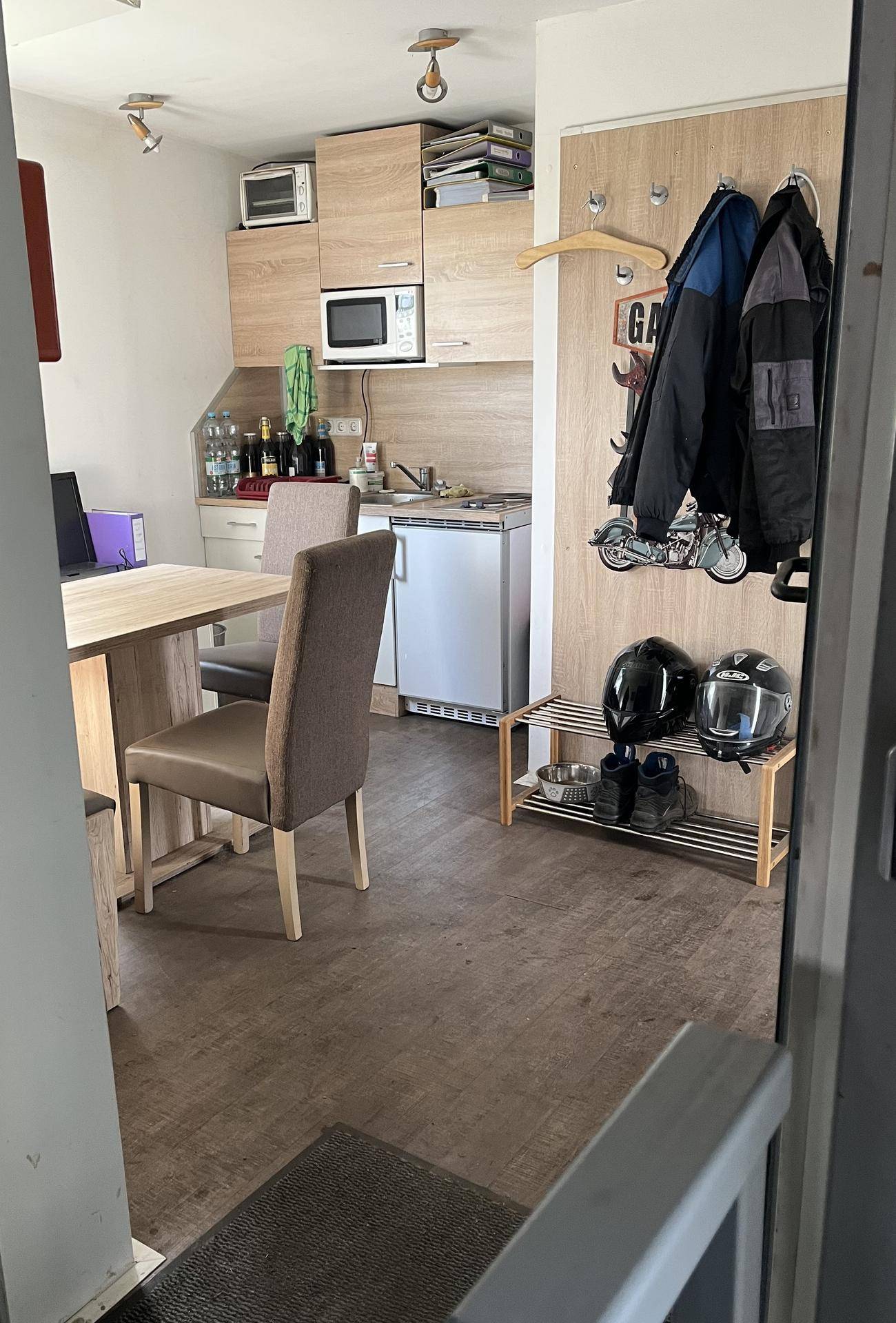 Kleiner Küchenbereich mit Esstisch und Garderobe im Eingangsbereich, funktional eingerichtet.