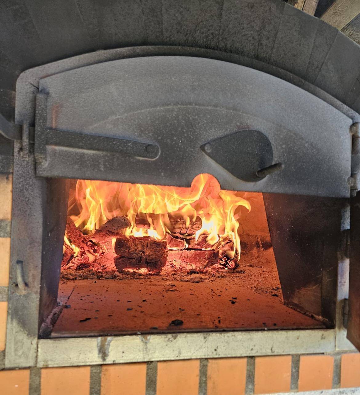 Nahaufnahme eines brennenden Feuers in einem gemauerten Ofen, der Wärme und Atmosphäre spendet.
