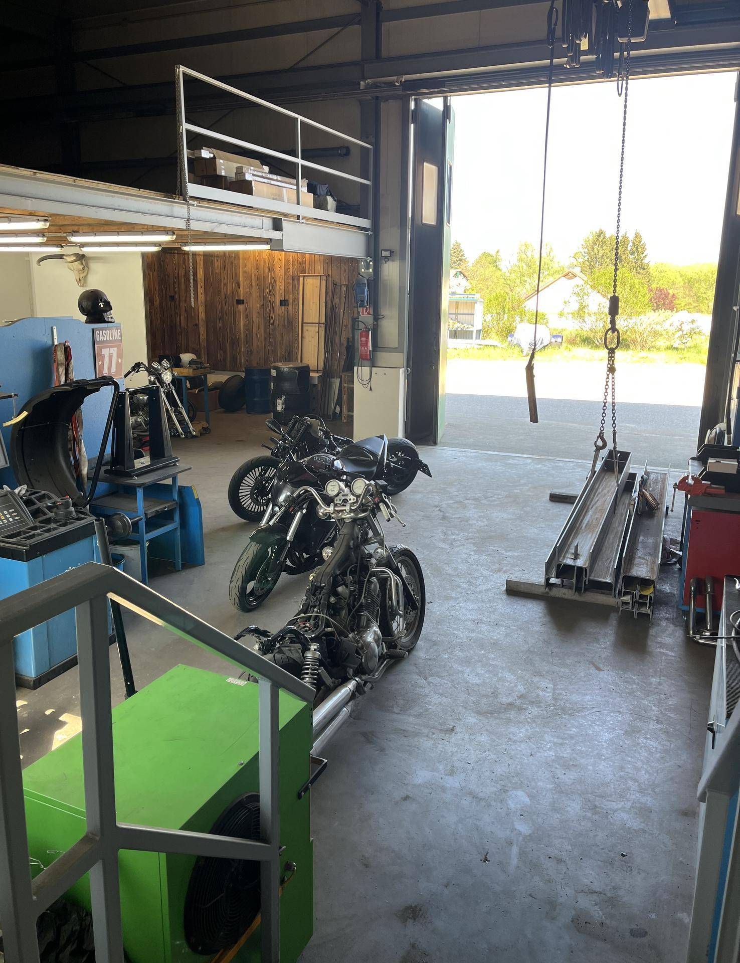 Geräumige Garage und Werkstatt mit Motorrädern, Hebebühnen und einer oberen Galerieebene.