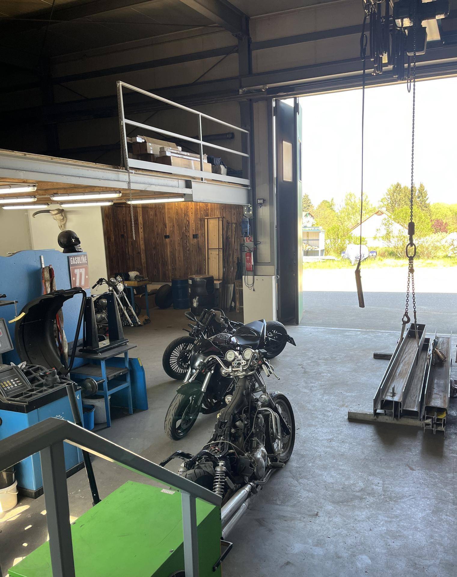 Geräumige Garage und Werkstatt mit Motorrädern, Hebebühnen und einer oberen Galerieebene.
