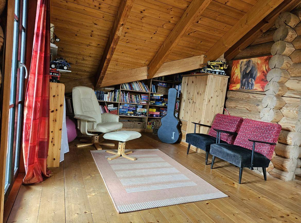 Raum im Obergeschoss des Blockhauses, möglicherweise Bibliothek oder Arbeitszimmer, mit schrägen Holzdecken und Holzboden.
