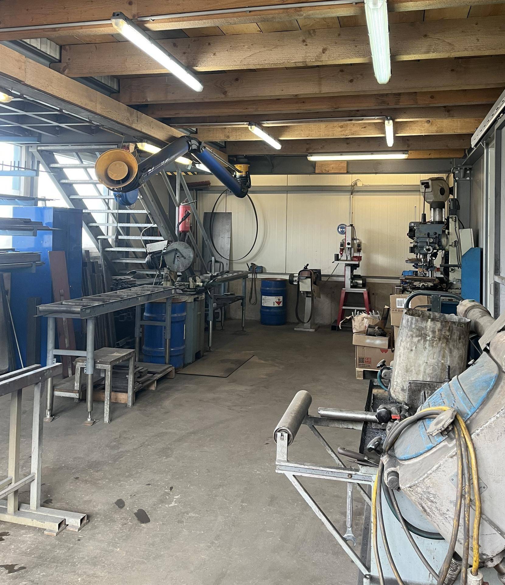 Werkstatt mit schweren Maschinen, Werkzeugen und einem robusten Betonboden, ideal für industrielle Arbeiten.