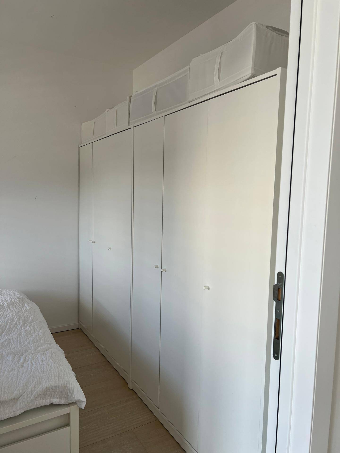 Geräumige weiße Einbauschränke im Schlafzimmer bieten viel Stauraum.