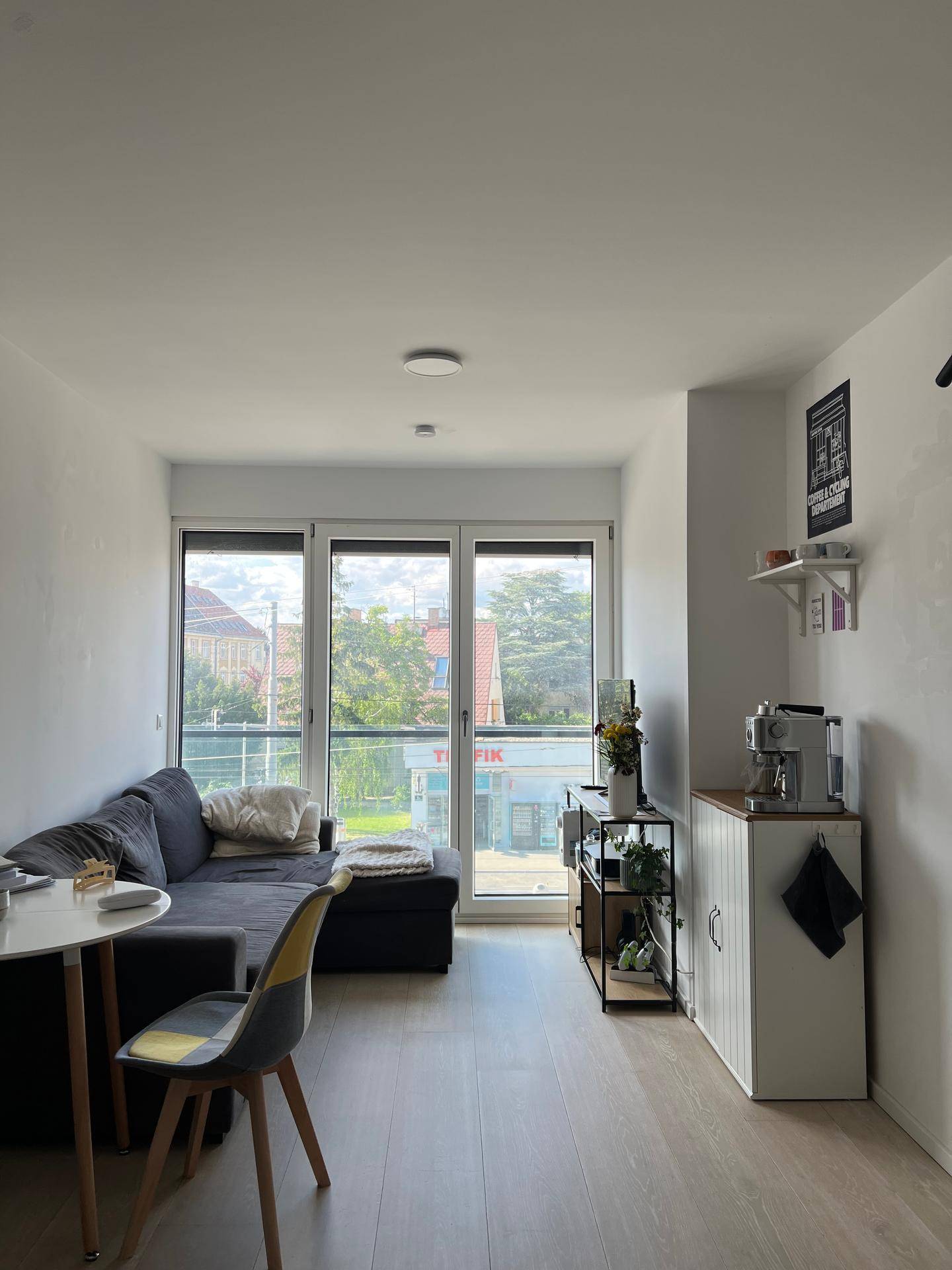 Gemütlicher Wohnbereich mit Sofa, Esstisch und großen Fenstern, die viel Tageslicht hereinlassen.