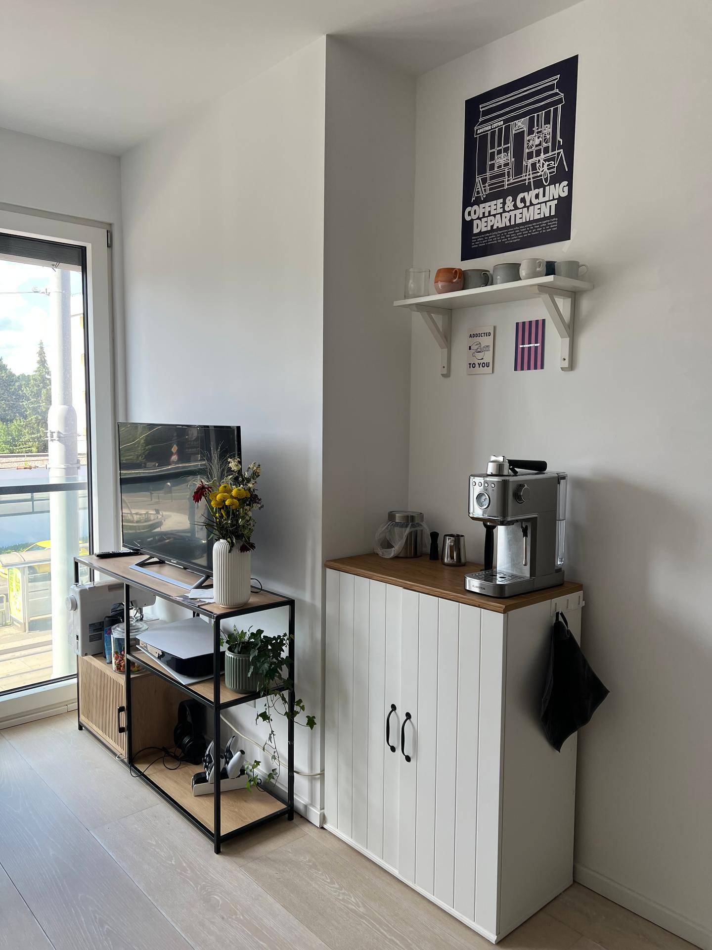 Moderner Beistellschrank mit Kaffeemaschine und Fernseher in einem hellen Wohnbereich.